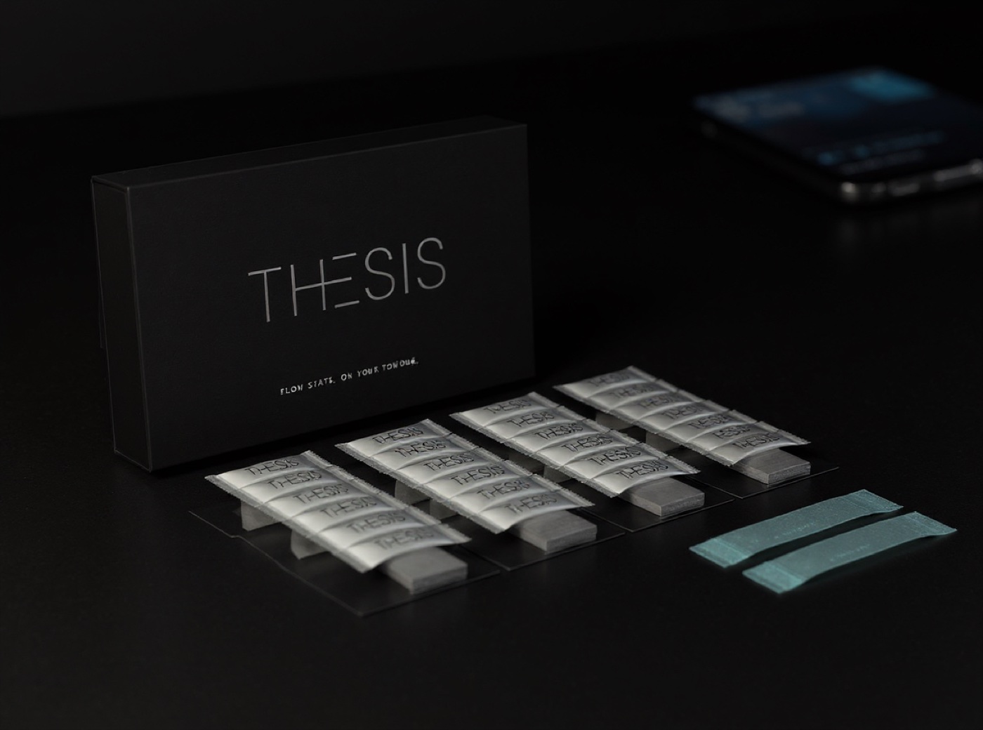 THESIS box and foil sticks on a desk beside a phone